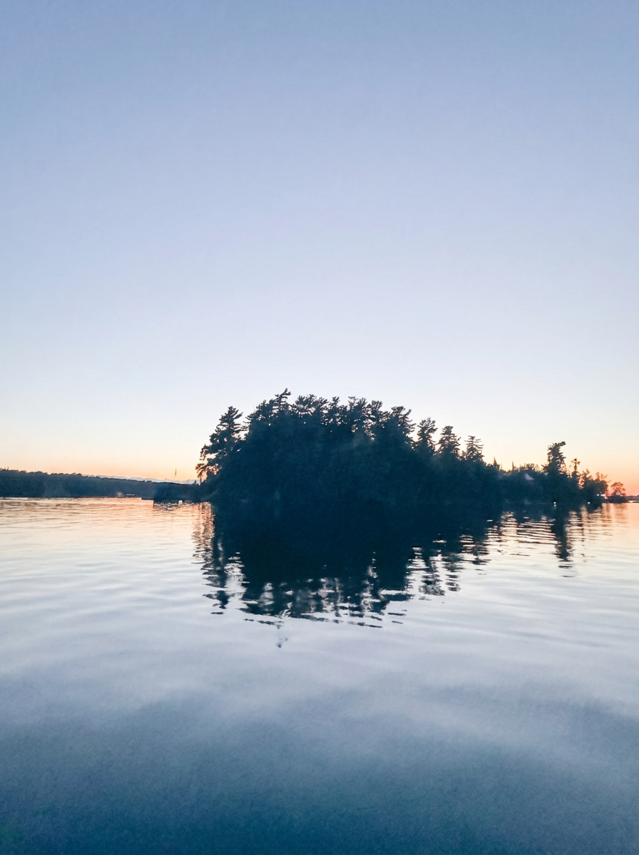 Two pines framing a calm lake at dawn on Lake of the Woods